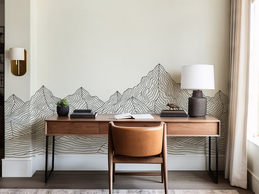 Modern home office with wooden desk, chair, and decorative mountain wall art.