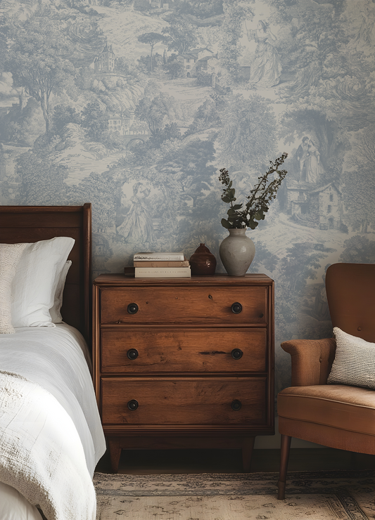 Bedroom with wooden dresser, floral arrangement, and armchair against a patterned wall.