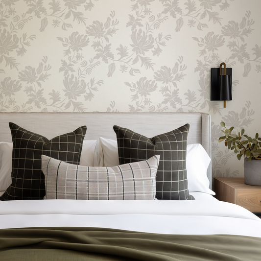 Bedroom with a bed featuring patterned pillows against a floral wallpaper wall.