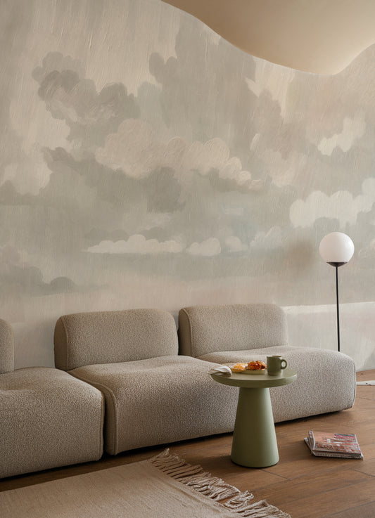 Modern living room with a beige sofa, small round table, and cloud-patterned wall.