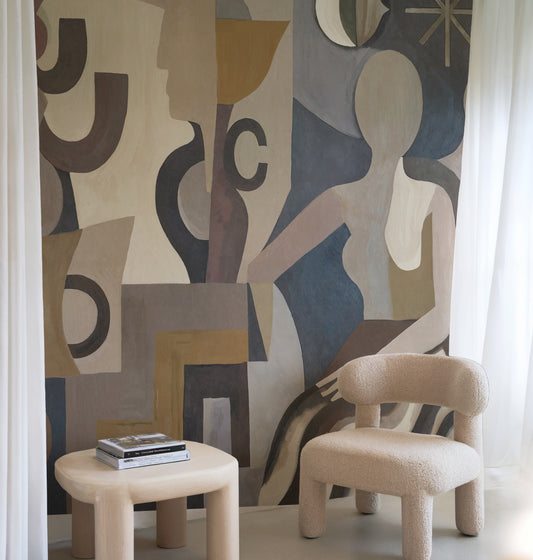 Beige chair and small table against a colorful abstract wall mural