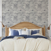 Bedroom with wooden headboard, blue and white bedding, and nautical-themed wallpaper.