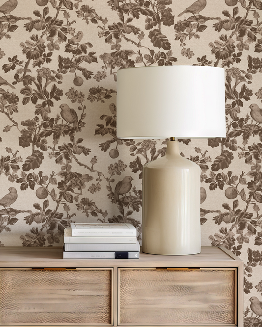 Decorative lamp and books on a wooden console table with floral wallpaper in the background