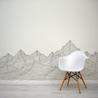 White chair in front of a wall with mountain line art design
