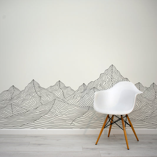 White chair in front of a wall with mountain line art design