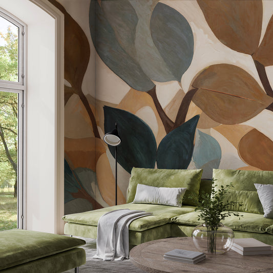 Green sofa with decorative pillows in a room with leaf-patterned wall and large window.