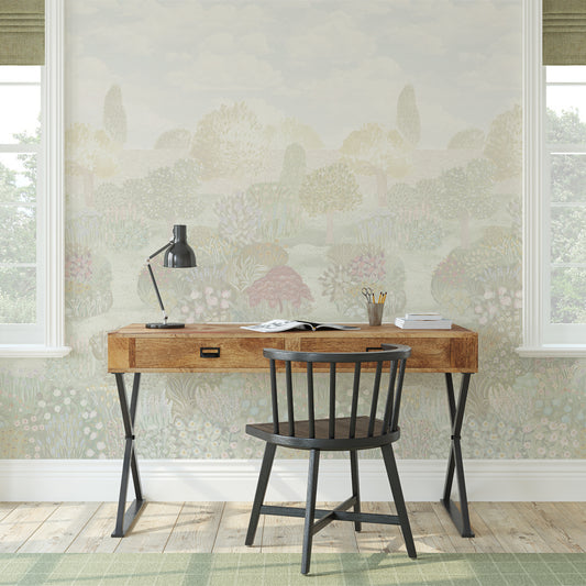 Wooden desk with black chair against a floral wallpapered wall.
